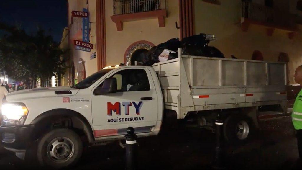 White MTY public service truck with a load of garbage bags in the bed at night with a worker in a reflective vest nearby and the slogan AQUÍ SE RESUELVE visible on the door   Informe Regio