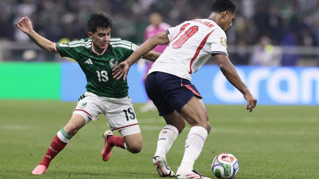 Two soccer players compete for the ball on a green field one in a green kit and the other in white with red details during a match close to the ball   Informe Regio