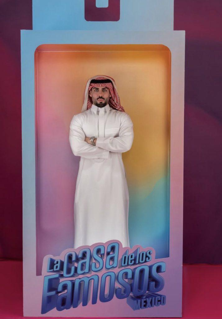 Masad-lcdlf-méxico - Informe Regio Man in a white thobe and red ghutra stands with arms crossed inside a colorful promotional box reading La Casa de los Famosos Mexico Informe Regio