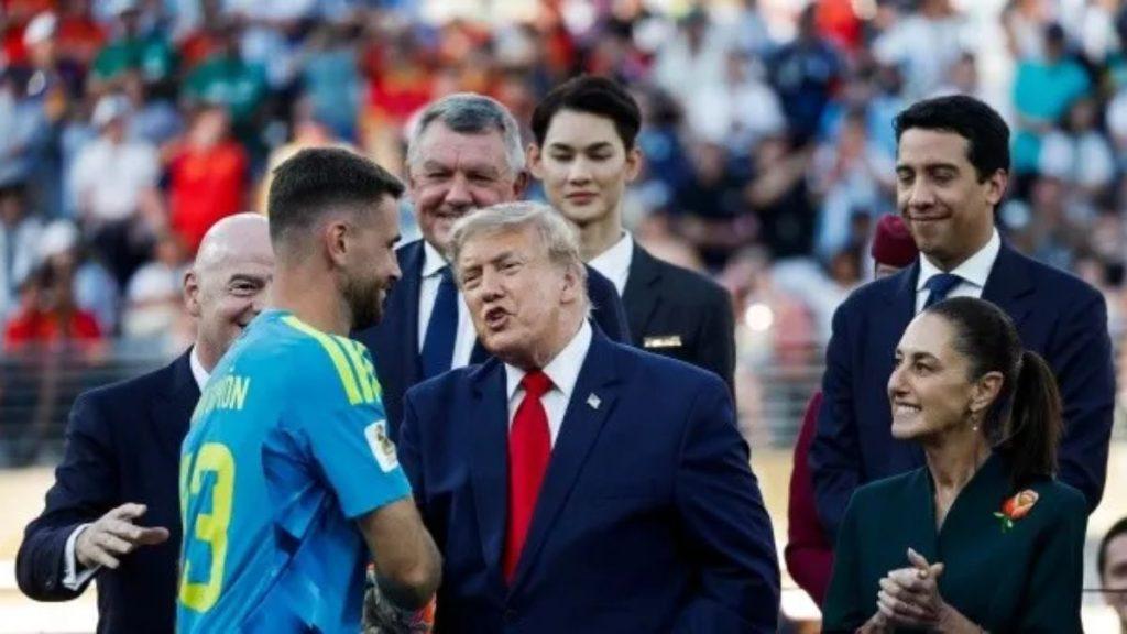 Saludo-sheinbaum-seleccion-argentina - Informe Regio A man in a dark suit and red tie converses with a footballer wearing a blue jersey on a stadium field with spectators in the background Informe Regio