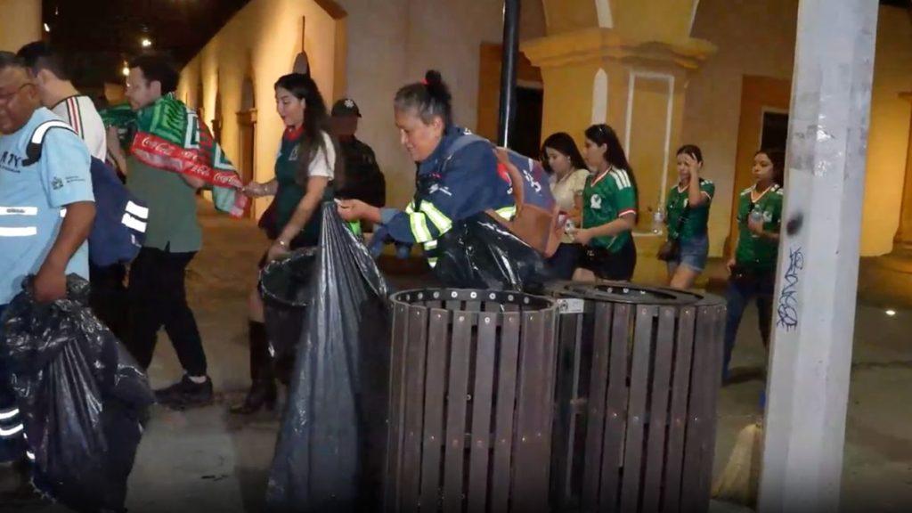 Nighttime city cleanup with volunteers carrying large black trash bags and placing them near metal trash cans   Informe Regio