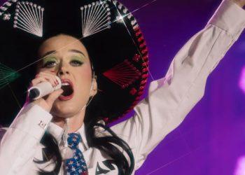 Katy-perry-san-luis - Informe Regio Performer wearing a large decorative sombrero singing into a microphone with one arm raised on a purple lit stage Informe Regio