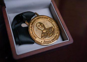 Gold medal resting in a wooden presentation box with a black ribbon attached to it   Informe Regio