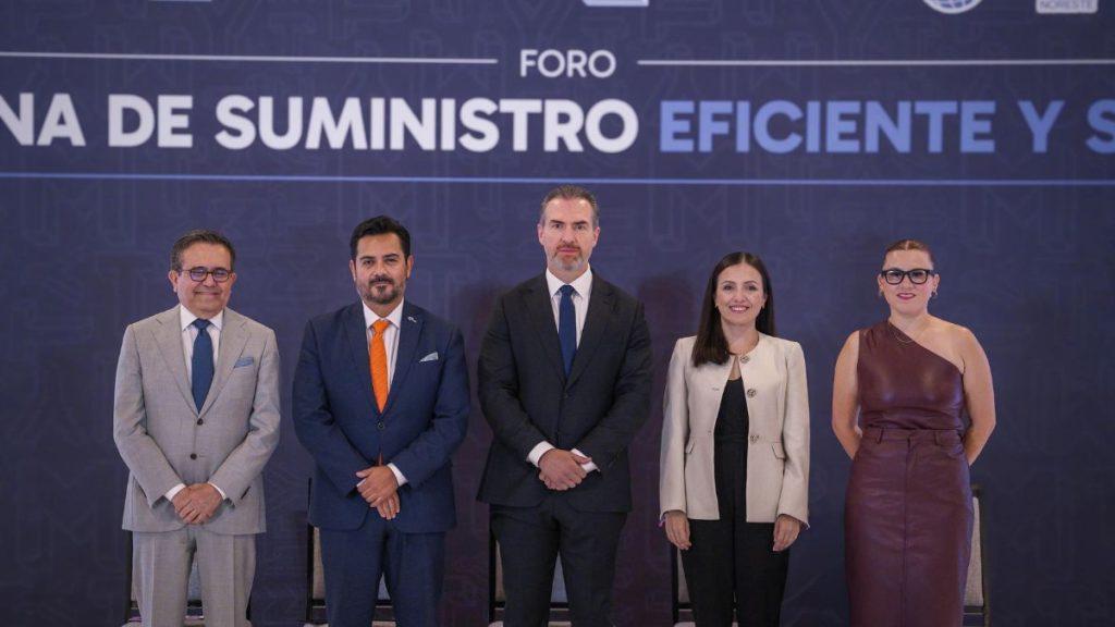 Alianza-comce-monterrey - Informe Regio Five professionals in formal attire pose on stage at a conference with a blue backdrop about efficient supply Informe Regio