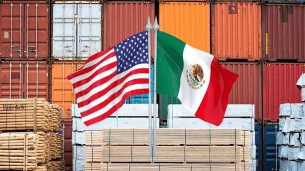 Aranceles-mexico-canada-trump - Informe Regio USA and Mexico flags flutter side by side in a shipping yard with stacked lumber and colorful containers in the background Informe Regio
