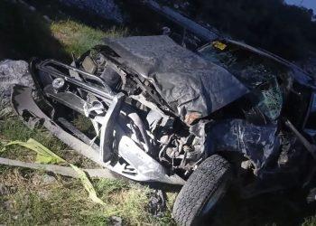 Front end of a severely crashed dark SUV on a grassy roadside at night with crumpled hood and exposed engine parts behind a yellow caution tape order of debris nearby   Informe Regio