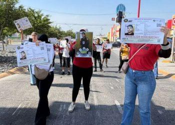 Garcia-alexis-aldair - Informe Regio Group of people marching on a street holding large missing person or identification flyers sunny day storefronts visible in background Informe Regio