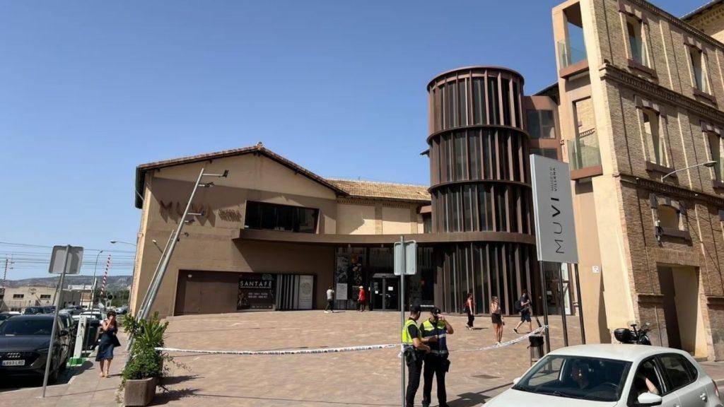 Street view of a beige building with a cylindrical glass tower and a vertical MUVI sign police tape blocks the sidewalk as two officers stand nearby and pedestrians pass by   Informe Regio