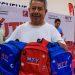Man smiles while handing out blue and red MTY backpacks at a charity event table full of backpacks behind him   Informe Regio