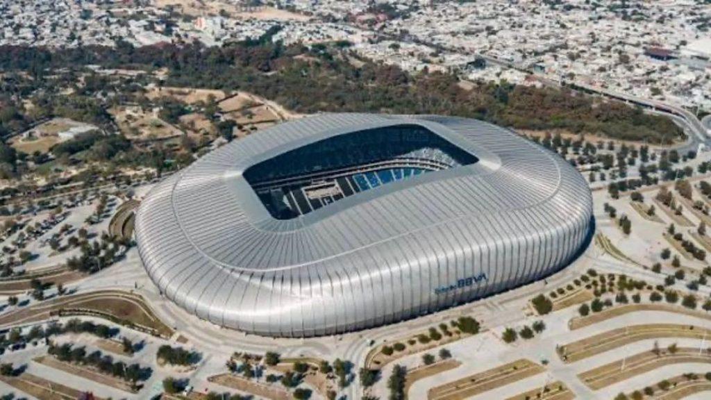 Aerial view of a large silver oval stadium with an open central roof and surrounding roads and landscape nearby   Informe Regio