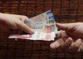 Two hands pass a stack of Mexican peso bills from one person to another showing various colorful notes like 100s and 200s in motion   Informe Regio