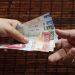 Two hands pass a stack of Mexican peso bills from one person to another showing various colorful notes like 100s and 200s in motion   Informe Regio