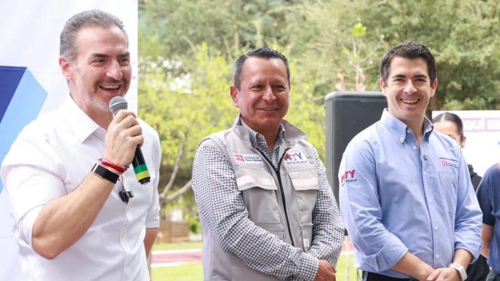 Three men stand outdoors at a daytime event the man on the left speaks into a microphone and smiles   Informe Regio