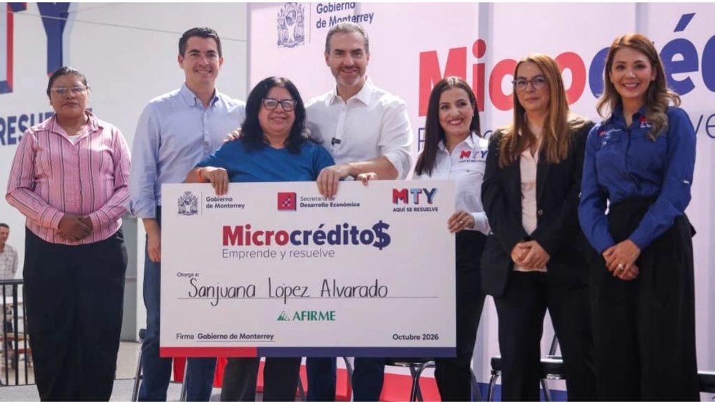 Informe-regio-colonias-de-monterrey-adrian-de-la-garzajpg - Informe Regio Group of seven people posing with an oversized Microcrédito check recipient Sanjuana Lopez Alvarado on a stage Informe Regio