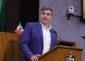 Man in a blue blazer and white shirt speaks at a wooden podium with two microphones a small Mexican flag is visible behind him   Informe Regio