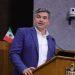 Man in a blue blazer and white shirt speaks at a wooden podium with two microphones a small Mexican flag is visible behind him   Informe Regio