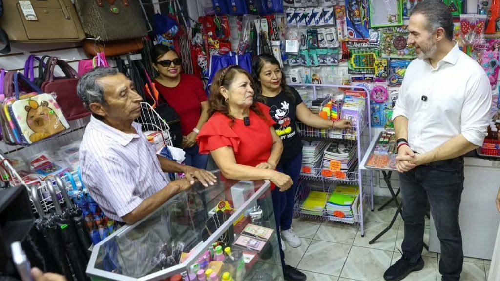 Group of five people chatting in a small shop a man in a white shirt talks with customers near a glass display counter full of items   Informe Regio