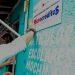 Man in a white shirt presses a sign onto a turquoise wall promoting a microcredit program Microcréditos   Informe Regio