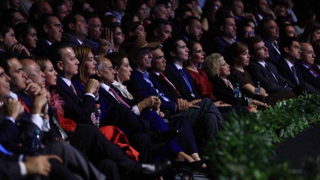 Informe-regio-monterrey-segundo-informe-adrian-de-la-garzajpg - Informe Regio Audience seated in rows at a formal event many in suits listening attentively with greenery in the foreground Informe Regio