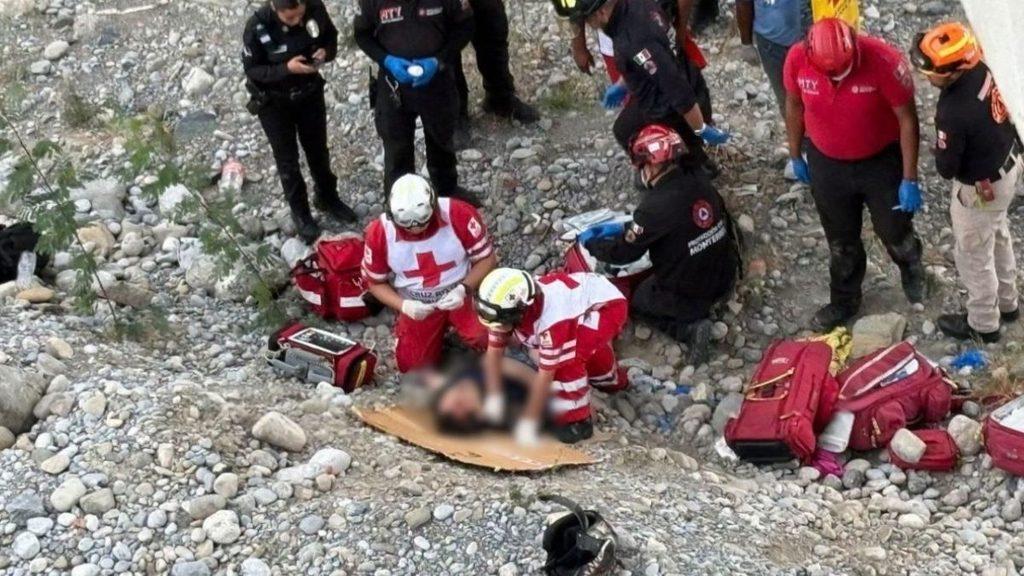 Paramedics in red cross uniforms treat an injured person lying on cardboard on a rocky outdoor site with rescue bags nearby   Informe Regio