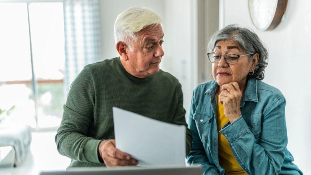 An older couple sits at a table indoors looking over a document together with attentive expressions   Informe Regio