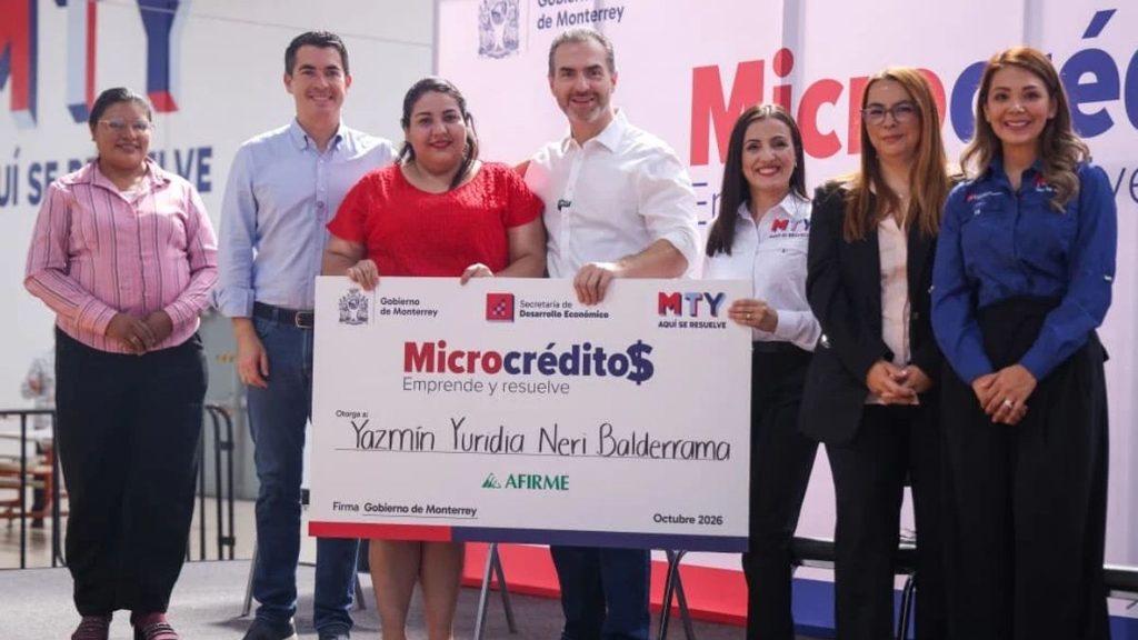 Informe-regio-préstamos-para-nuevos-negocios-regiosjpg - Informe Regio Seven people stand on a stage holding a large ceremonial check for Microcrédito awarded to Yazmín Yuridia Neri Balderrama with government logos in the background Informe Regio