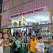 Crowd lines up outside a religious shrine at night behind a decorative gate and a storefront sign that reads Antiguorio de San Judas Tadeo   Informe Regio