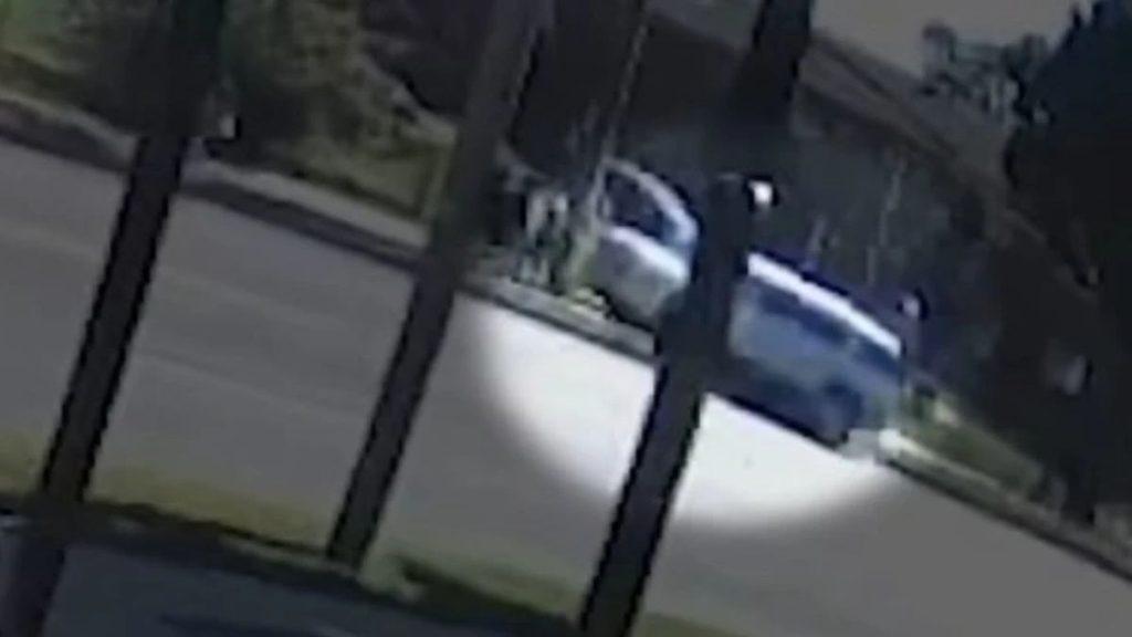 Blurry street scene with a blue car parked on the curb seen through foreground fence posts in a suburban neighborhood   Informe Regio