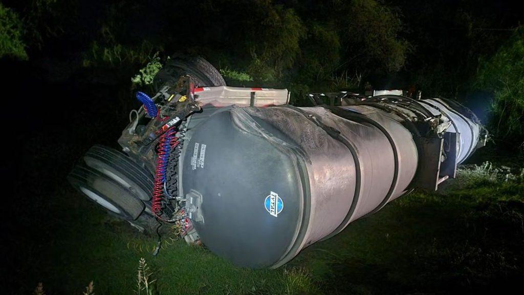 Overturned gray fuel tanker on its side at night with exposed hoses and a wheel visible on the left in a grassy area   Informe Regio